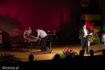 Foto: Marek Szumowski i Jarosław Cholewicki wyciągają klawiaturę z fortepianu a Jacek Szymański prowadzi koncert