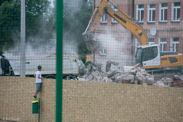 Chłopiec przez ogrodzenie ogląda burzenie sali gimnastycznej