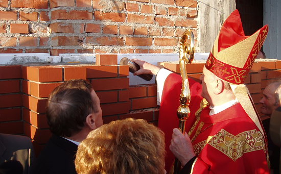 Ks. bp Stanisław Stefanek wkłada dokument w metalowej tubie w otwór w fasadzie kościoła pw. Św. Andrzeja Boboli