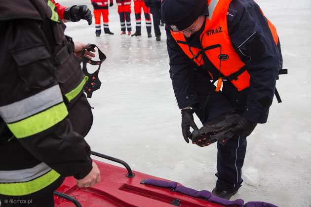 Policjant zakłada specjalne kolce do chodzenia po lodzie