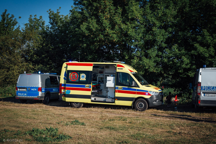 Pogotowie ratunkowe i samochody policji nad Narwią, w miejscu gdzie z wody wyciągnięto 55-letniego mieszkańca Łomży